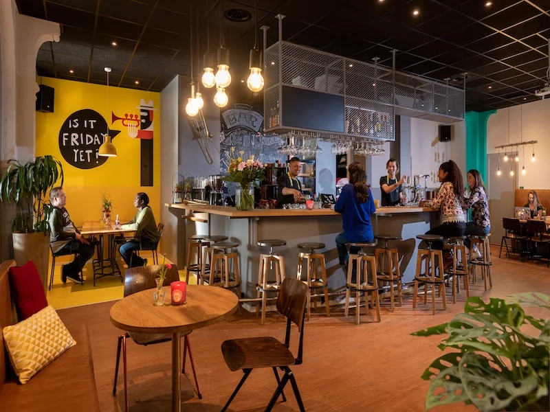 Stayokay Den Haag interieur met bar en zitplaatsen Interieur van Stayokay Den Haag met tafels, stoelen en een bar
